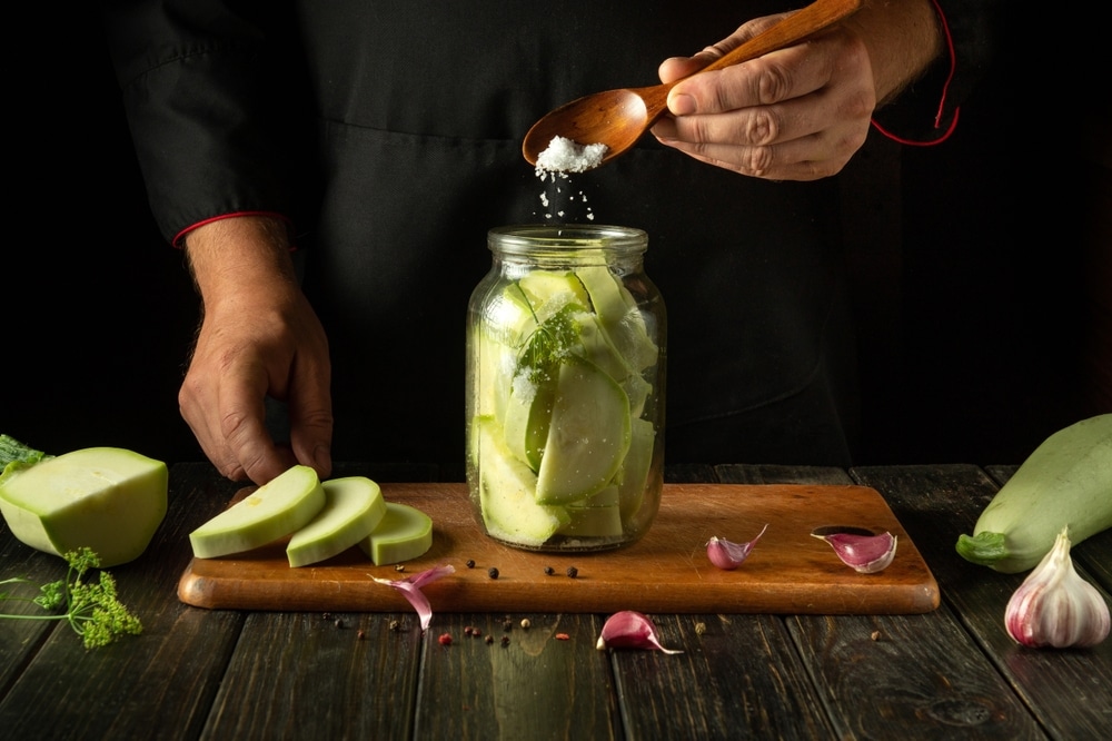 A view of a person adding some sugar to the pickle solution