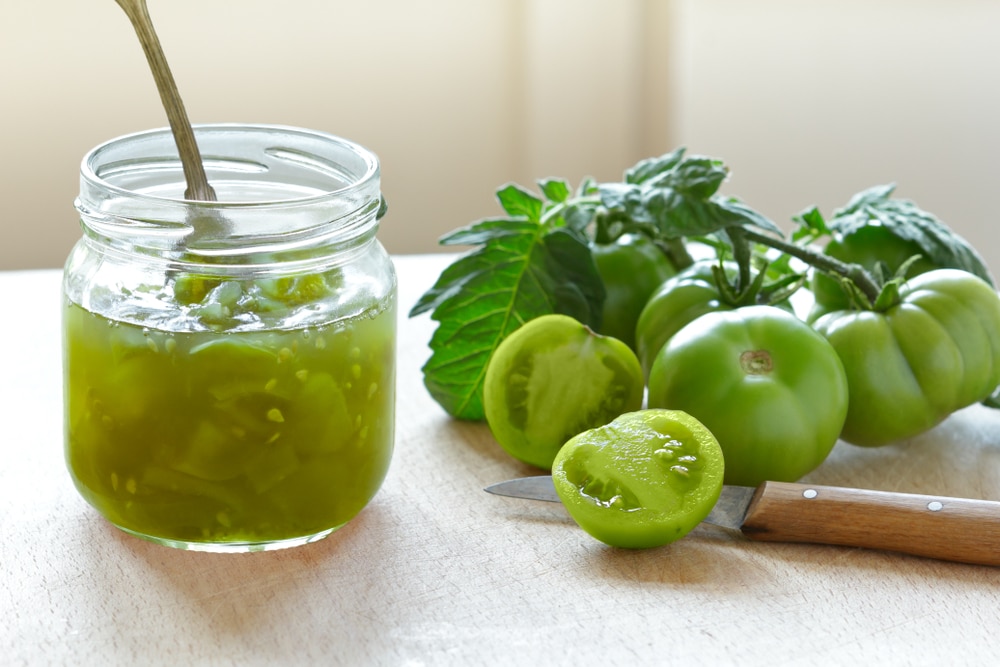 A view of canned green tomatoes along with some in raw form on the side