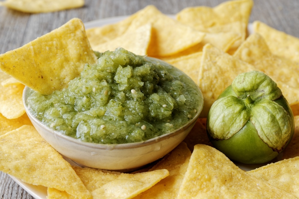 A view of green salsa verde with nachos in it