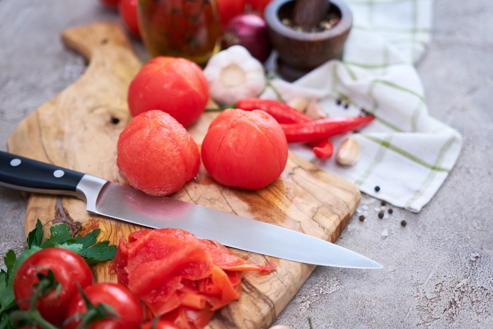 A view of peeled tomatoes with knife on the side