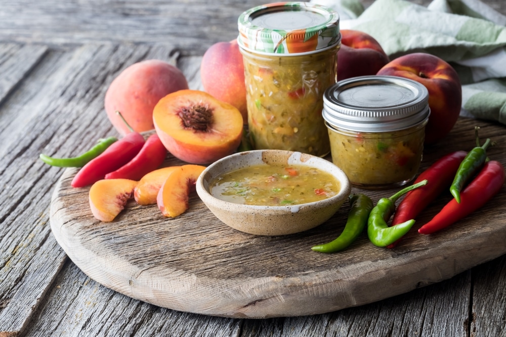 Jars Of Peach And Peppers Salsa Surrounded By Ingredients Used