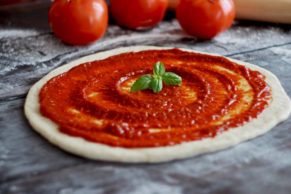 Raw Pizza Dough With Tomato Sauce And Basil Leaves Selective