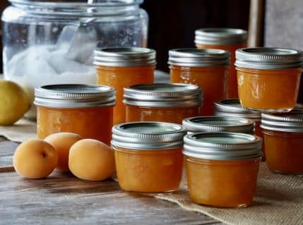 A view of a apricot jam canned alongside a few apricots