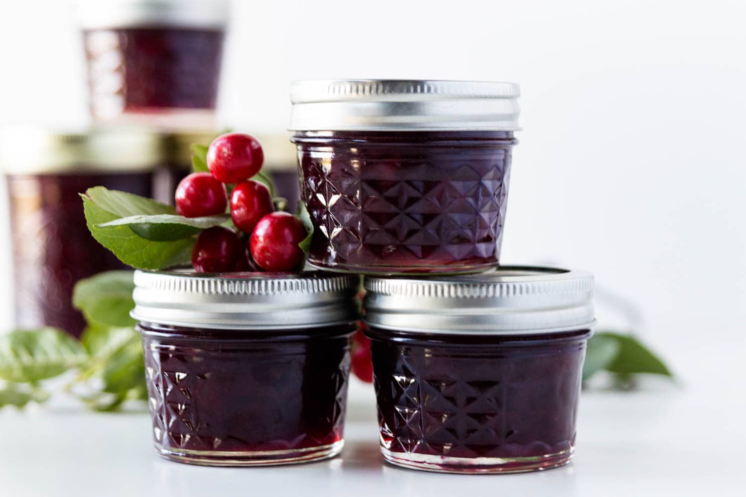 A view of three cans with cherry jam and cherries on the lid