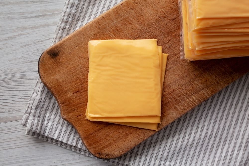 Yellow Cheddar American Cheese Stacked Slices On A Wooden Board