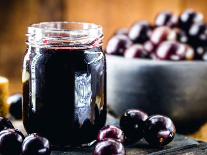 a jar fillled with grape jelly along with black grapes