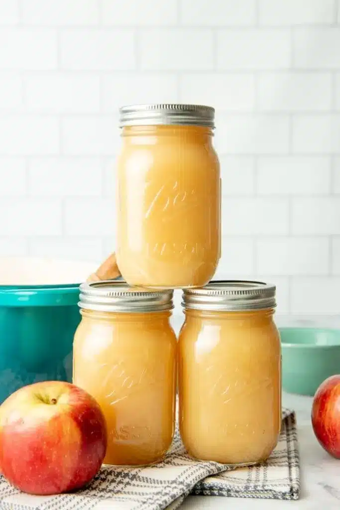 jars of apple sauce placxed on a cloth with an apple