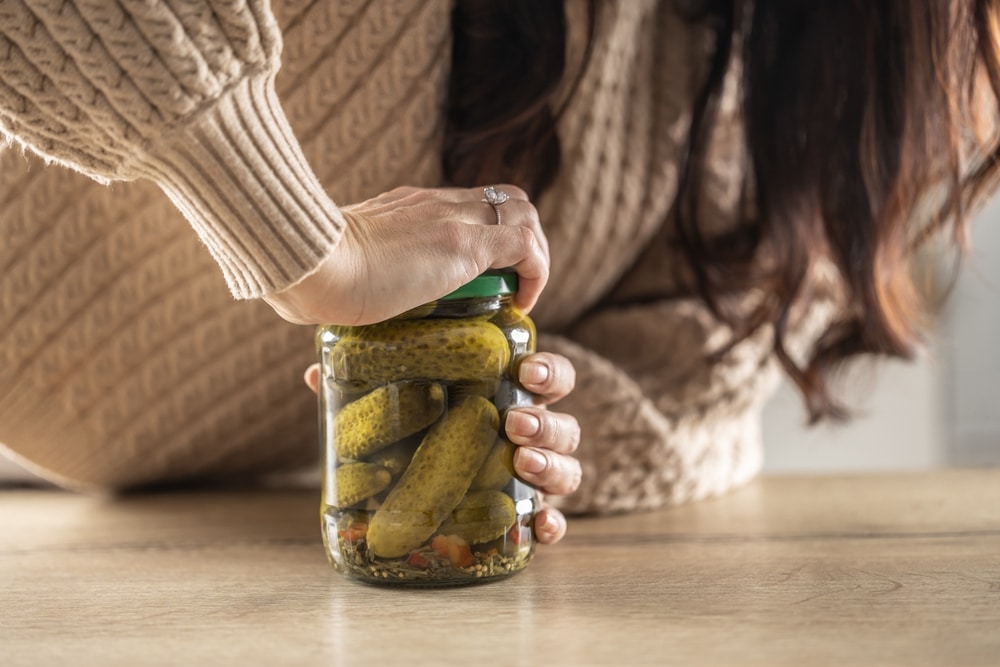 A Woman Tries To Force Open A Jam Jar With