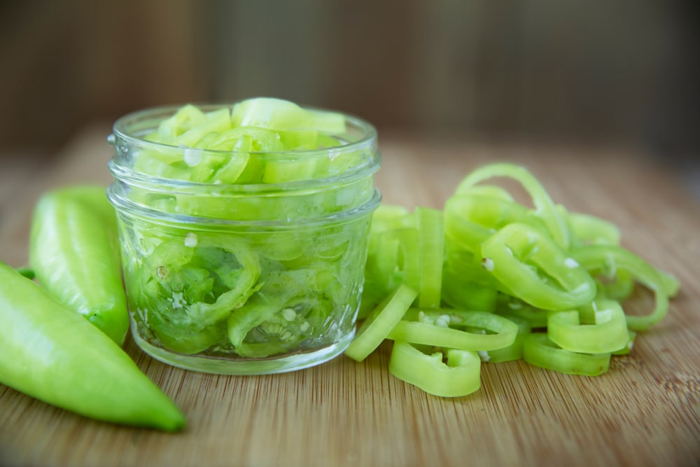 Fresh Sliced Banana Peppers On A Cutting Board With Jar