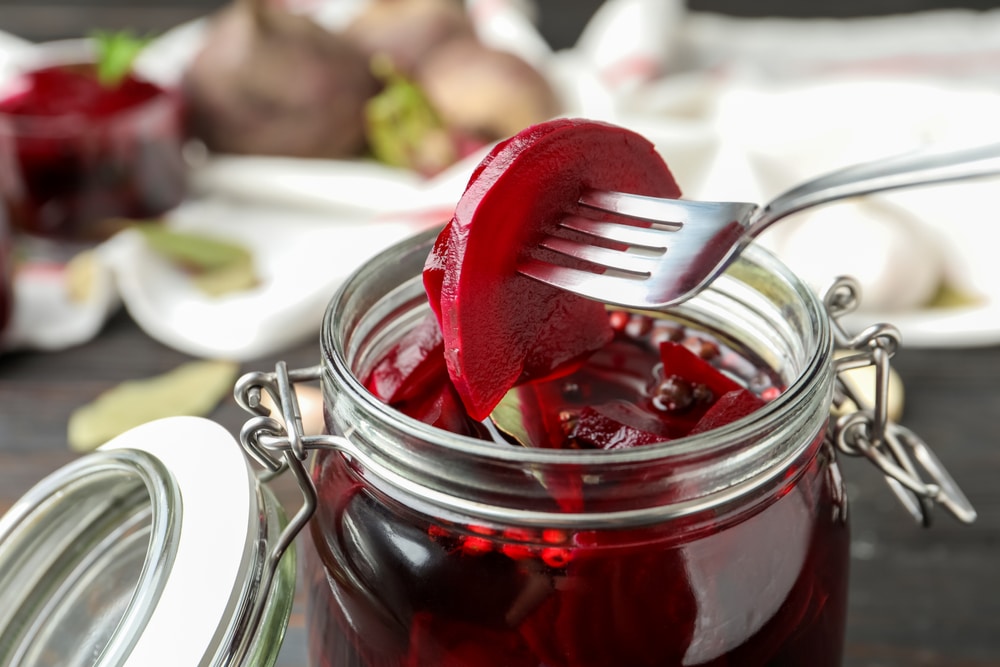 Fork With Pickled Beets Over Glass Jar On Wooden Table