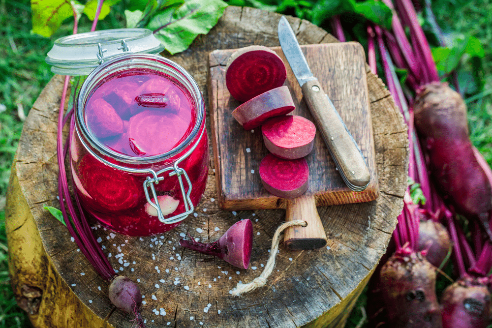 sliced beets on the wooden board with a jar of canned beets