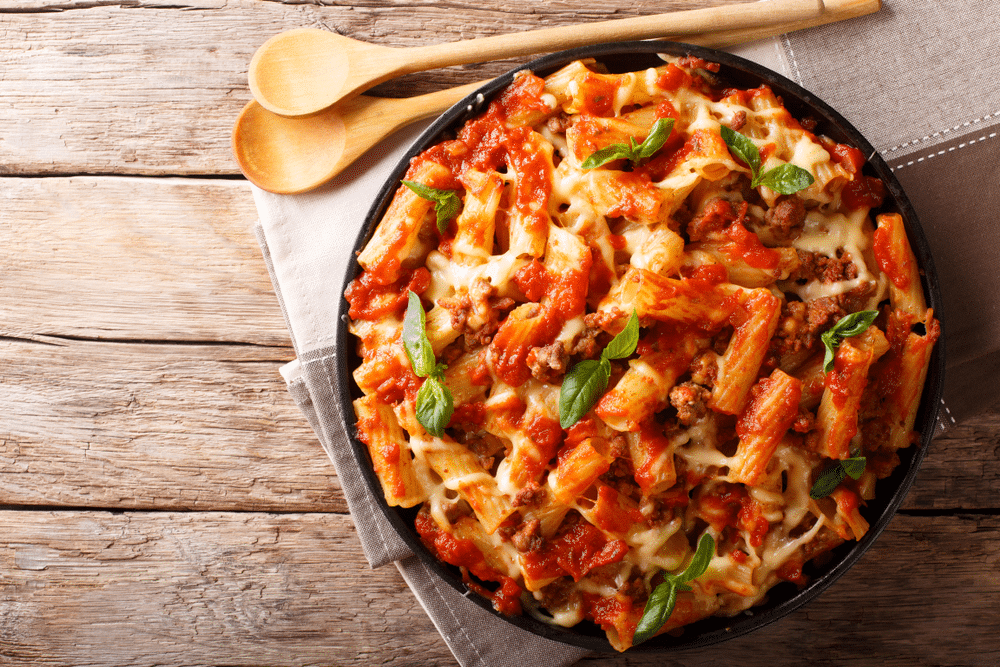 Pasta ziti with bolognese sauce and cheese close up on the table